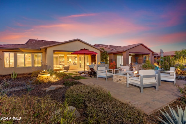 back of property featuring stucco siding, an outdoor living space with a fire pit, and a patio