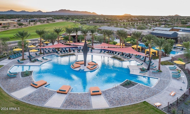 pool at dusk featuring a community pool and a mountain view