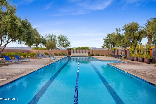 community pool featuring a fenced backyard, a mountain view, and a patio