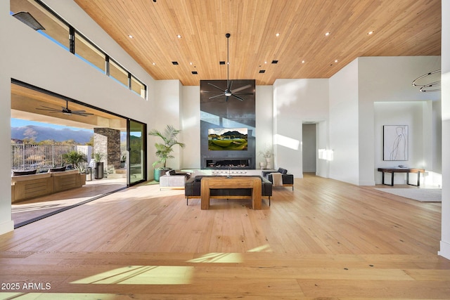 playroom with a high ceiling, wood ceiling, a fireplace, and light hardwood / wood-style flooring