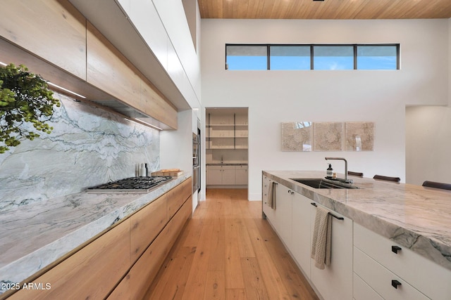 kitchen featuring sink, wood ceiling, appliances with stainless steel finishes, light stone counters, and white cabinets