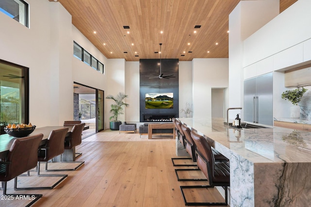 interior space with a high ceiling, sink, wood ceiling, and light hardwood / wood-style flooring