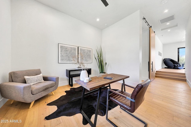 office space with light hardwood / wood-style floors, a barn door, and ceiling fan