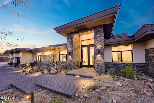 exterior entry at dusk featuring a patio area