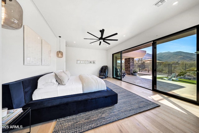 bedroom with ceiling fan, a mountain view, hardwood / wood-style floors, and access to outside