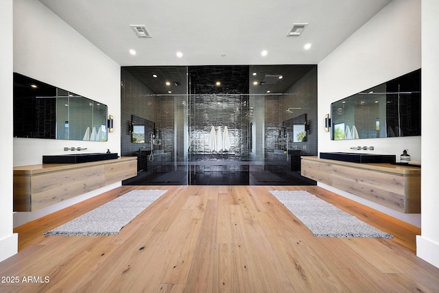 bathroom featuring hardwood / wood-style flooring, a healthy amount of sunlight, vanity, and a high ceiling