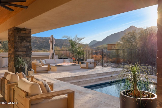 view of swimming pool with a mountain view, an outdoor living space with a fire pit, and ceiling fan