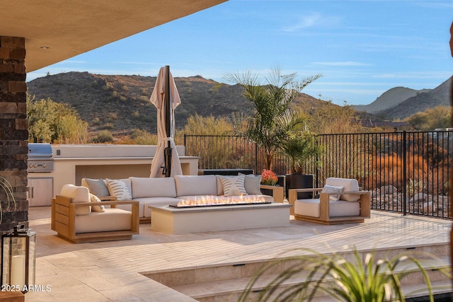 view of patio featuring area for grilling, a mountain view, an outdoor hangout area, and an outdoor kitchen