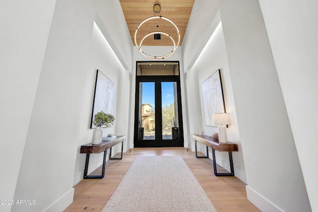 foyer entrance featuring wood ceiling, a towering ceiling, and light hardwood / wood-style floors