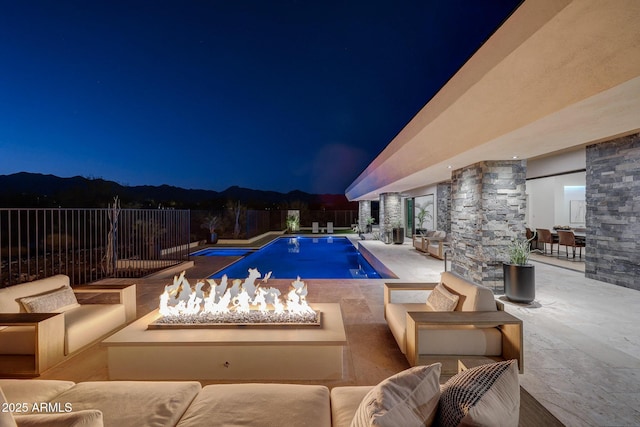 pool at twilight featuring an outdoor living space with a fire pit and a patio area