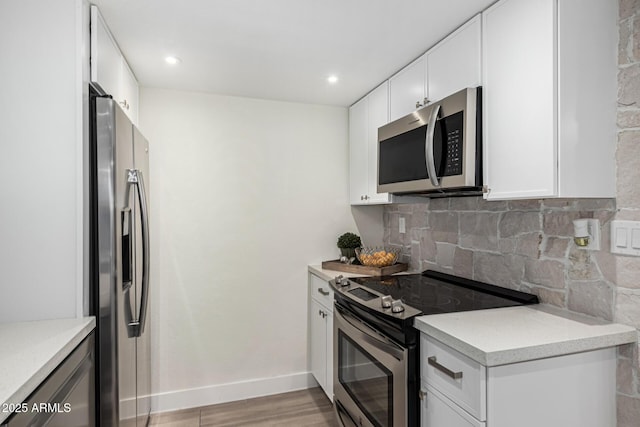 kitchen featuring stainless steel appliances, decorative backsplash, white cabinetry, and light hardwood / wood-style flooring