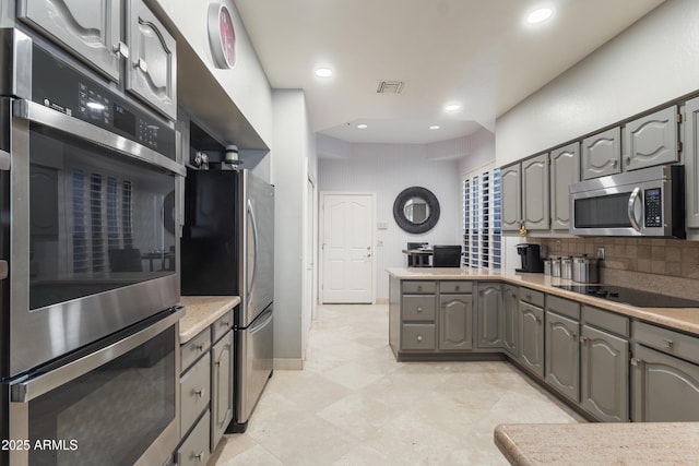 kitchen with backsplash, gray cabinets, and appliances with stainless steel finishes