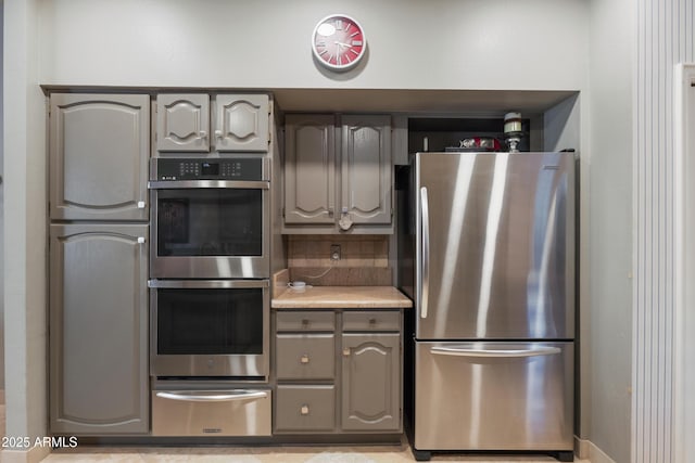 kitchen featuring decorative backsplash, gray cabinets, and stainless steel appliances