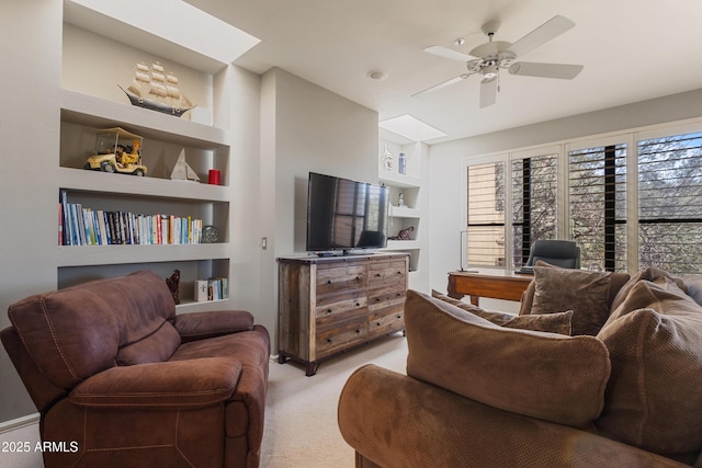 carpeted living room with a skylight, built in features, and ceiling fan