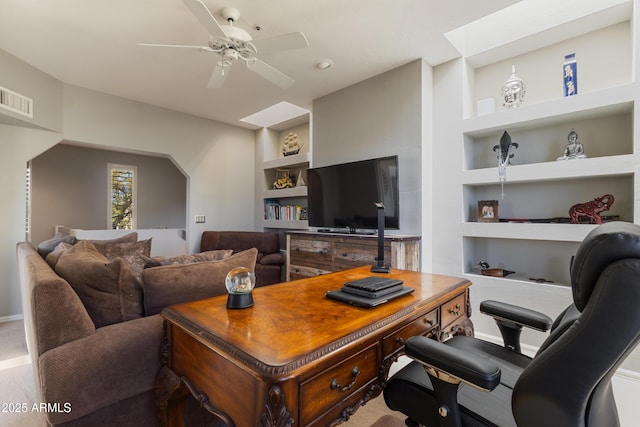 living room with built in shelves, ceiling fan, and a skylight