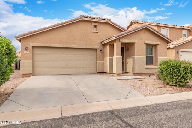view of front facade featuring stucco siding, an attached garage, driveway, and a tile roof