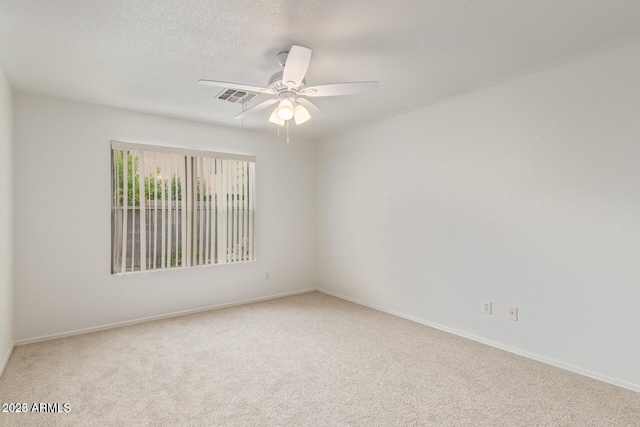 carpeted spare room featuring ceiling fan, visible vents, and baseboards