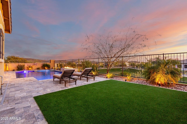 yard at dusk with a fenced in pool, pool water feature, and a patio area