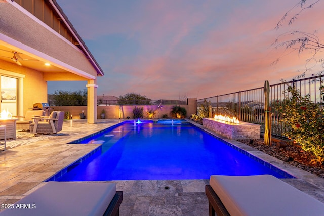 pool at dusk with a patio, pool water feature, and an outdoor fire pit