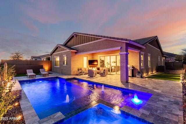 back house at dusk with an outdoor living space, pool water feature, a pool with hot tub, and a patio area