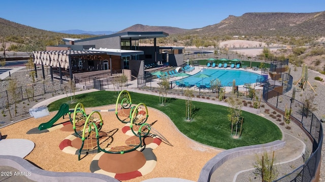 view of pool with a playground and a mountain view