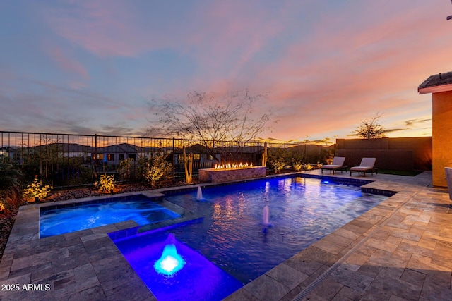 pool at dusk featuring an in ground hot tub, pool water feature, and a patio