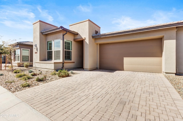 view of front facade with a garage, decorative driveway, and stucco siding