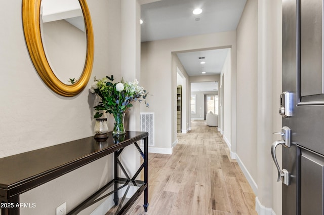 hall featuring light wood finished floors, baseboards, visible vents, and recessed lighting