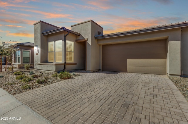 view of front of house with a garage, decorative driveway, and stucco siding
