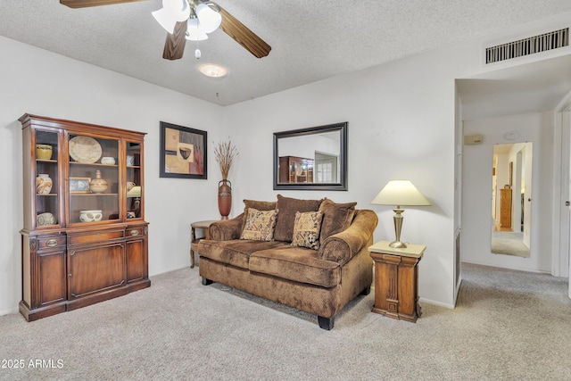 carpeted living room with visible vents, ceiling fan, and a textured ceiling