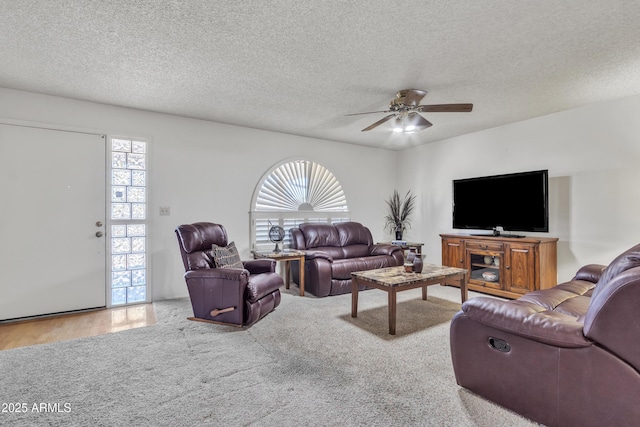 carpeted living room featuring a textured ceiling and a ceiling fan