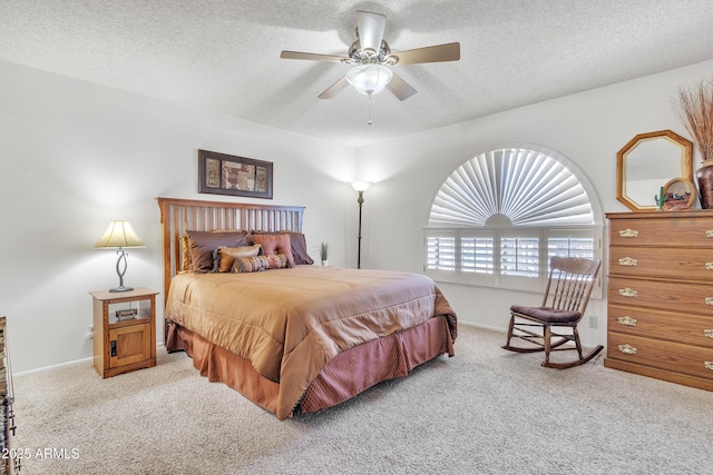 bedroom with baseboards, a ceiling fan, a textured ceiling, and light colored carpet