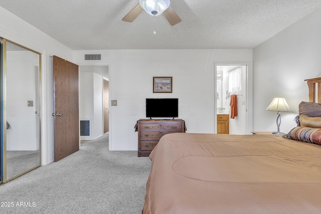 bedroom featuring visible vents, a ceiling fan, ensuite bath, a textured ceiling, and carpet floors