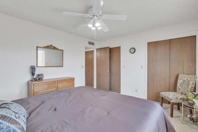 carpeted bedroom with visible vents and a ceiling fan