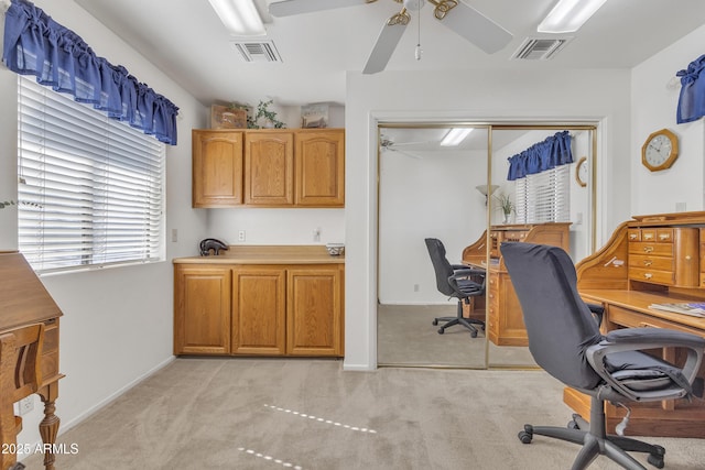 office featuring light carpet, ceiling fan, visible vents, and baseboards