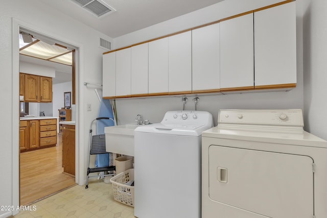 clothes washing area with light floors, cabinet space, visible vents, and washing machine and clothes dryer