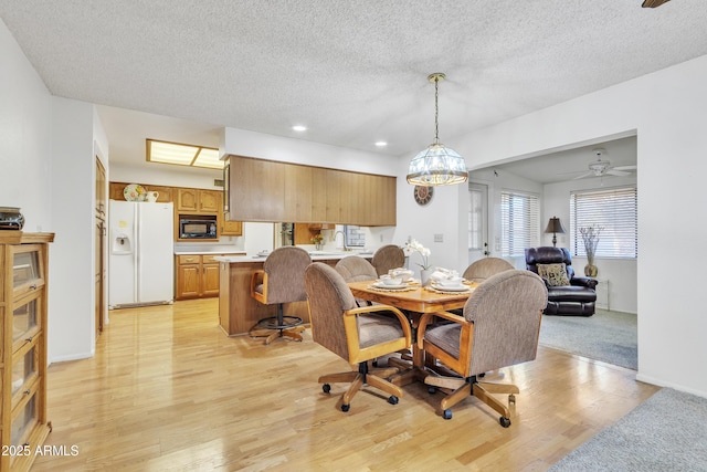 dining area with light wood-type flooring, a textured ceiling, and recessed lighting