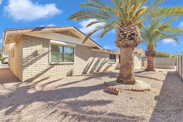 exterior space featuring brick siding and fence