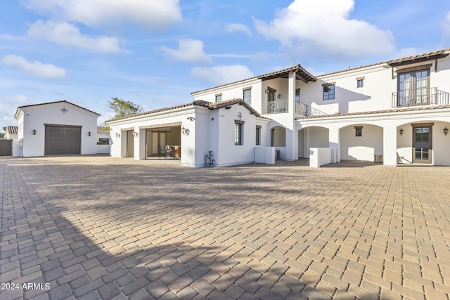 mediterranean / spanish home with a garage, a balcony, and an outbuilding