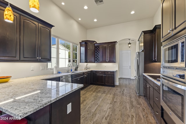10125 E Cortez Dr, Scottsdale, AZ 85260 - kitchen featuring appliances with stainless steel finishes, dark brown cabinetry, light stone countertops, recessed lighting, and a peninsula