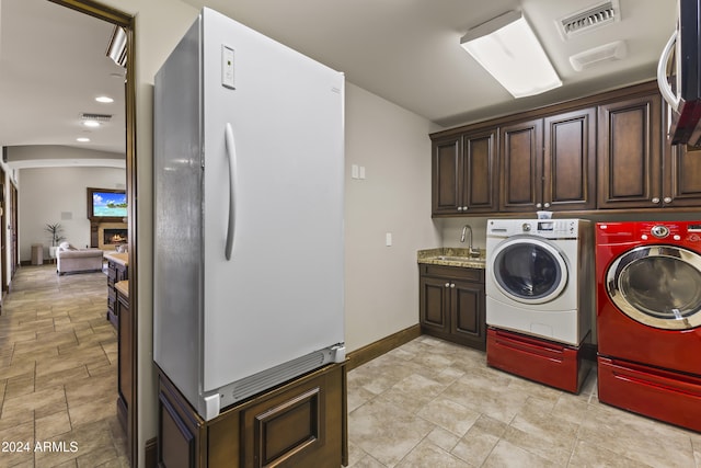 10125 E Cortez Dr, Scottsdale, AZ 85260 - laundry area with washer and dryer, cabinet space, a warm lit fireplace, and light stone finish flooring