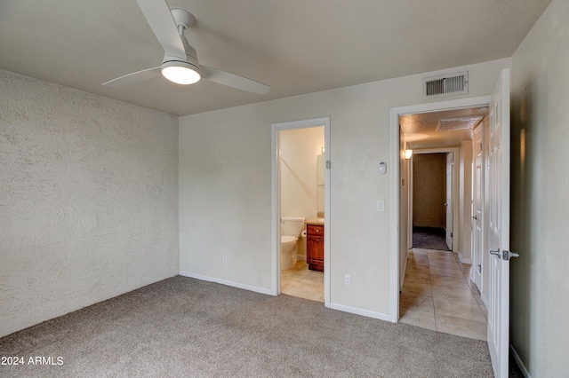 unfurnished bedroom with ensuite bath, ceiling fan, and light carpet