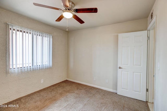 unfurnished room with ceiling fan, light carpet, and a wealth of natural light