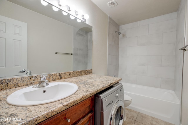 full bathroom featuring tiled shower / bath combo, tile patterned flooring, washer / clothes dryer, toilet, and vanity