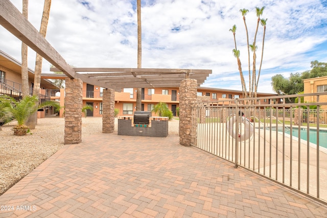 view of patio featuring a pergola, an outdoor kitchen, grilling area, and a community pool