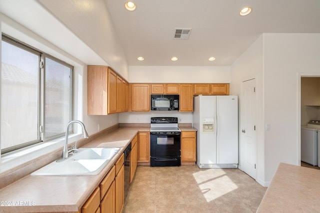 kitchen with sink, light tile patterned floors, black appliances, and washing machine and clothes dryer