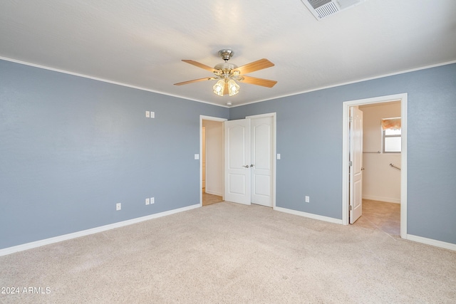 unfurnished bedroom featuring ornamental molding, light colored carpet, ceiling fan, and ensuite bathroom