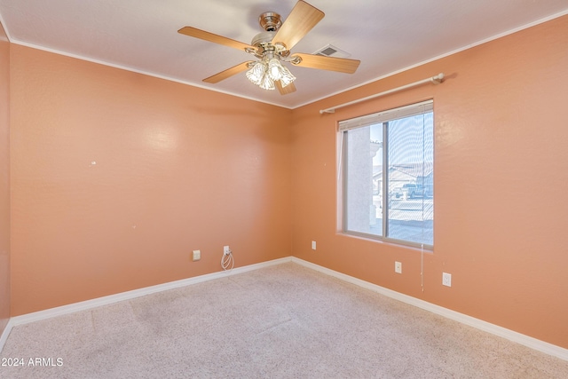 empty room with crown molding, ceiling fan, and carpet