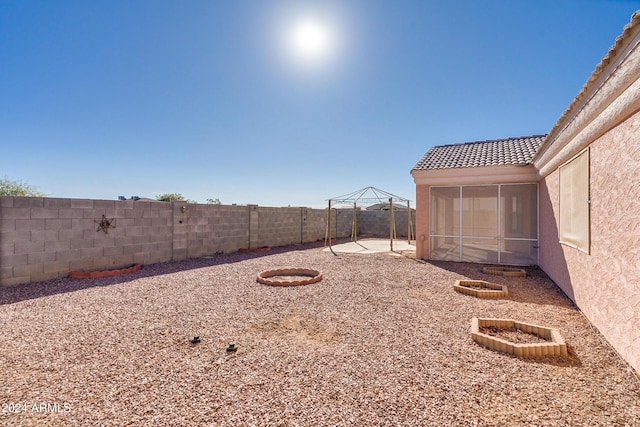 view of yard featuring a gazebo, an outdoor fire pit, a sunroom, and a patio