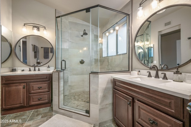 bathroom featuring a shower stall, visible vents, two vanities, and a sink